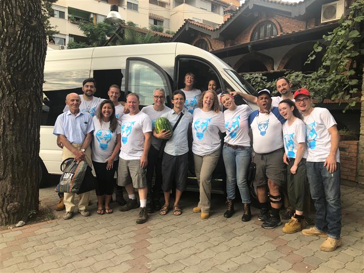 A group of people are posing for a picture in front of a van.