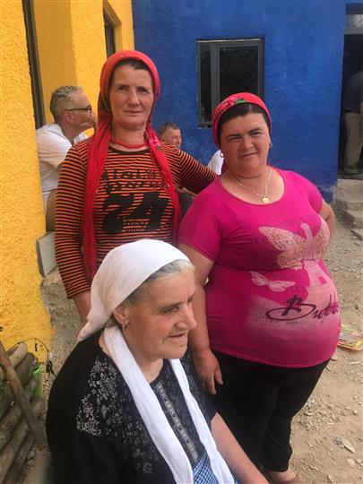 Three women are posing for a picture in front of a blue building