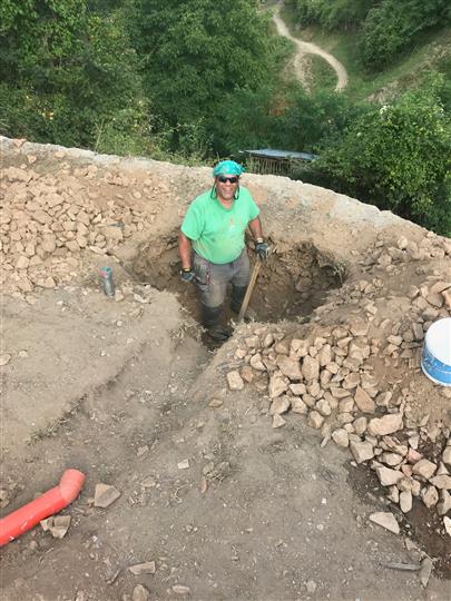 A man is digging a hole in the ground with a shovel.