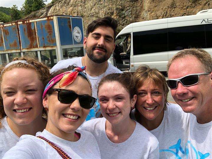 A group of people are posing for a picture in front of a white van.