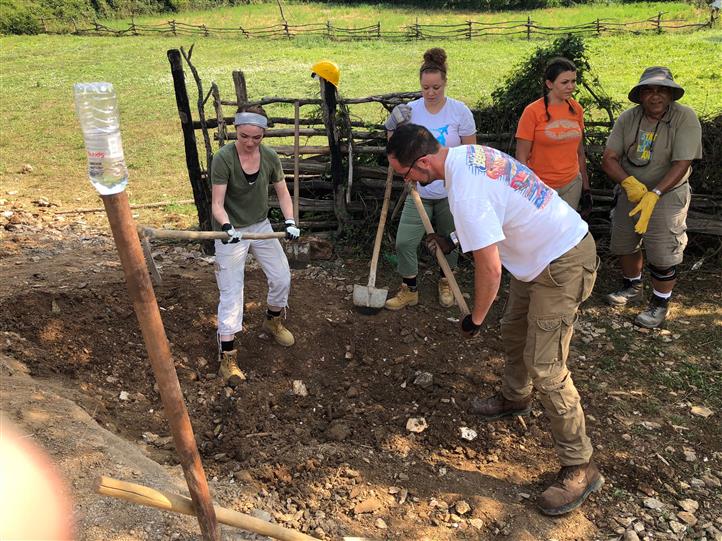 A group of people are digging in the dirt in a field.