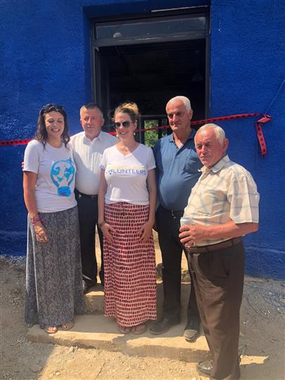 A group of people standing in front of a blue building