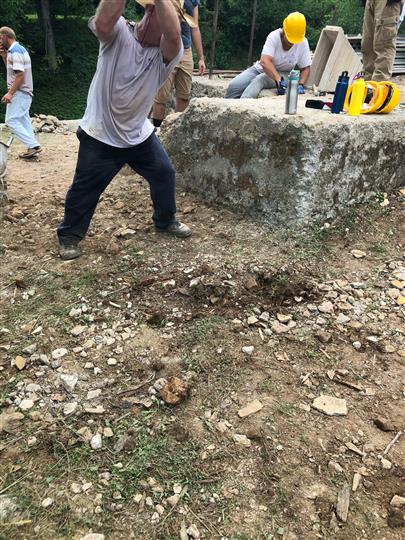 A group of construction workers are working on a large rock.