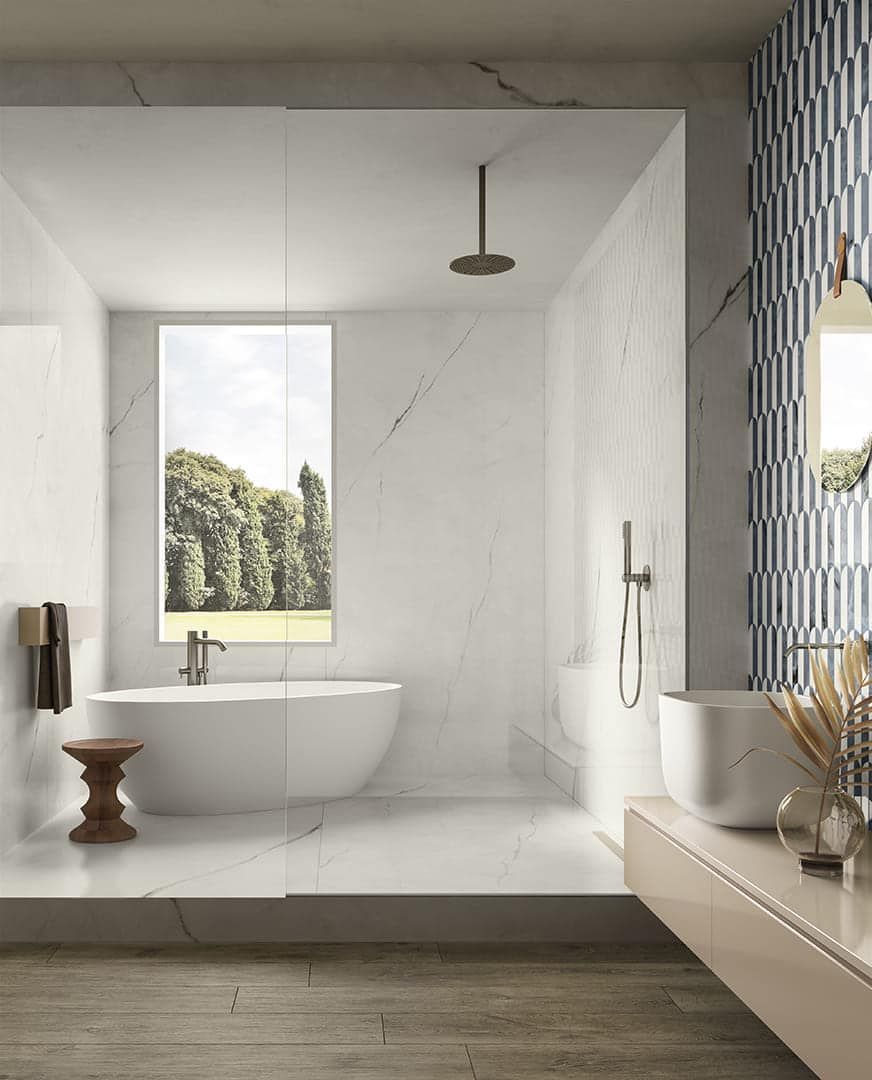 Bagno moderno con pareti in marmo, vasca indipendente e box doccia in vetro.