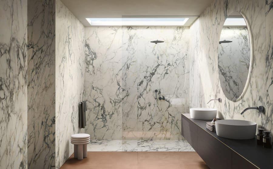 Lussuoso bagno in marmo con lucernario, doccia, doppio lavabo e pavimento color rame.