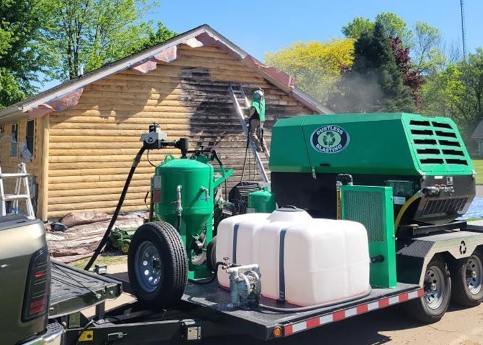 A man is using a pressure washer to clean a driveway in front of a house.