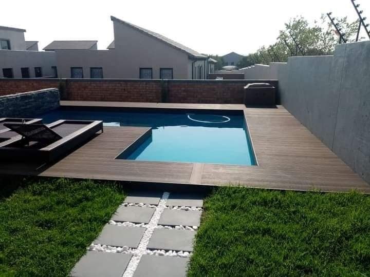 Curving swimming pool with red brickwork edging. Blue water, clear sky, outdoor setting.