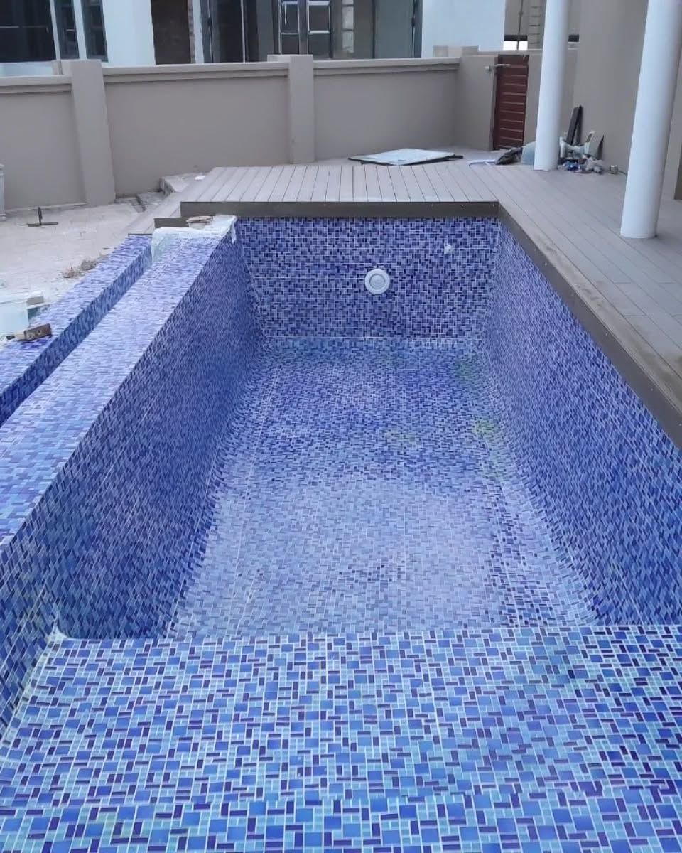 Blue tiled swimming pool under construction outdoors.