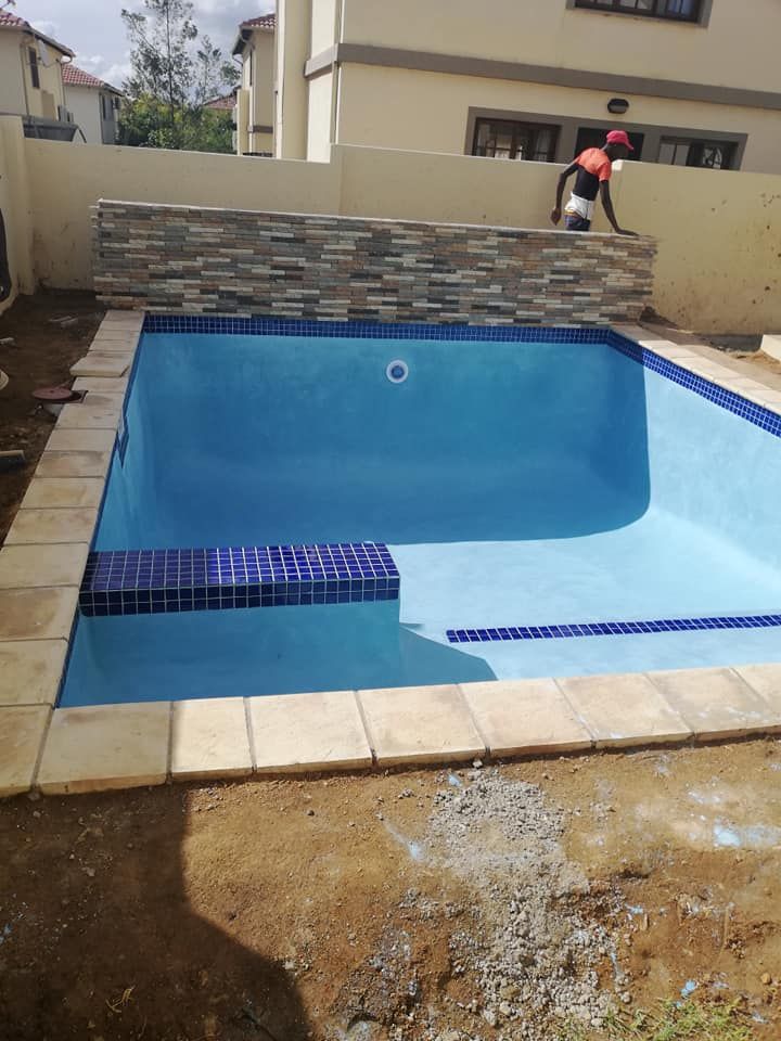 Blue tiled swimming pool under construction outdoors.