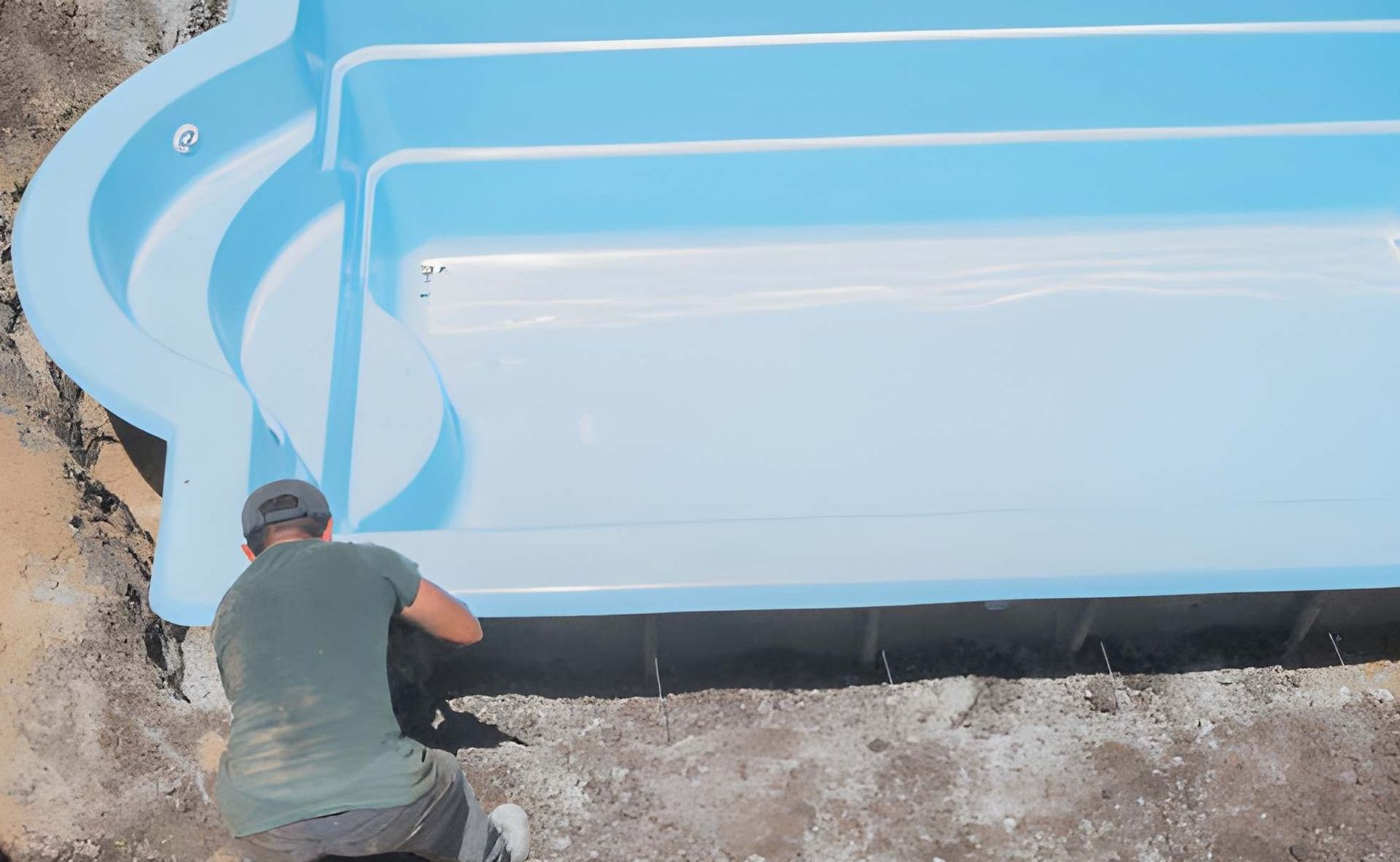 Small rectangular pool with blue water surrounded by a dark gray deck, white potted plants, and a dark wall.