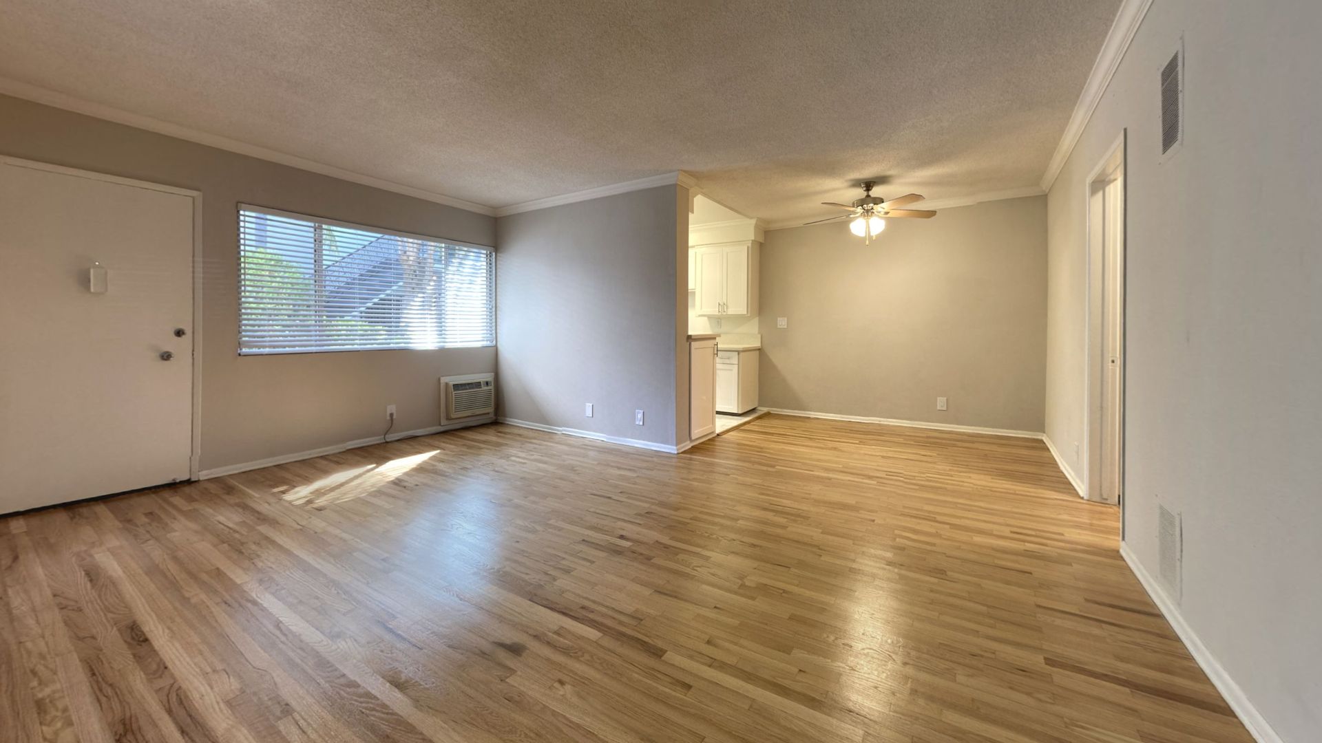 Empty apartment interior with hardwood floors and neutral paint.