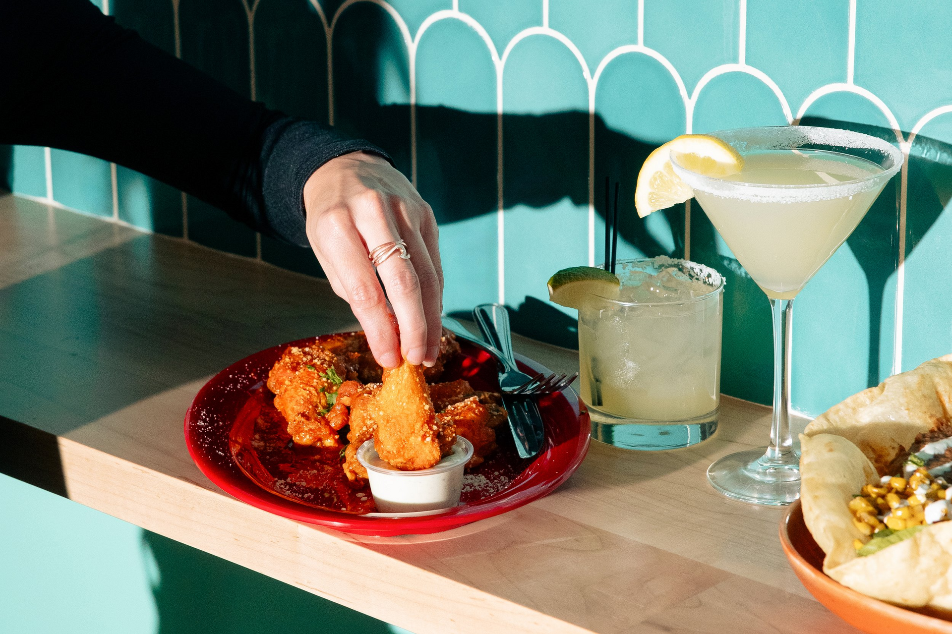 A person is dipping a piece of fried chicken into a dipping sauce.