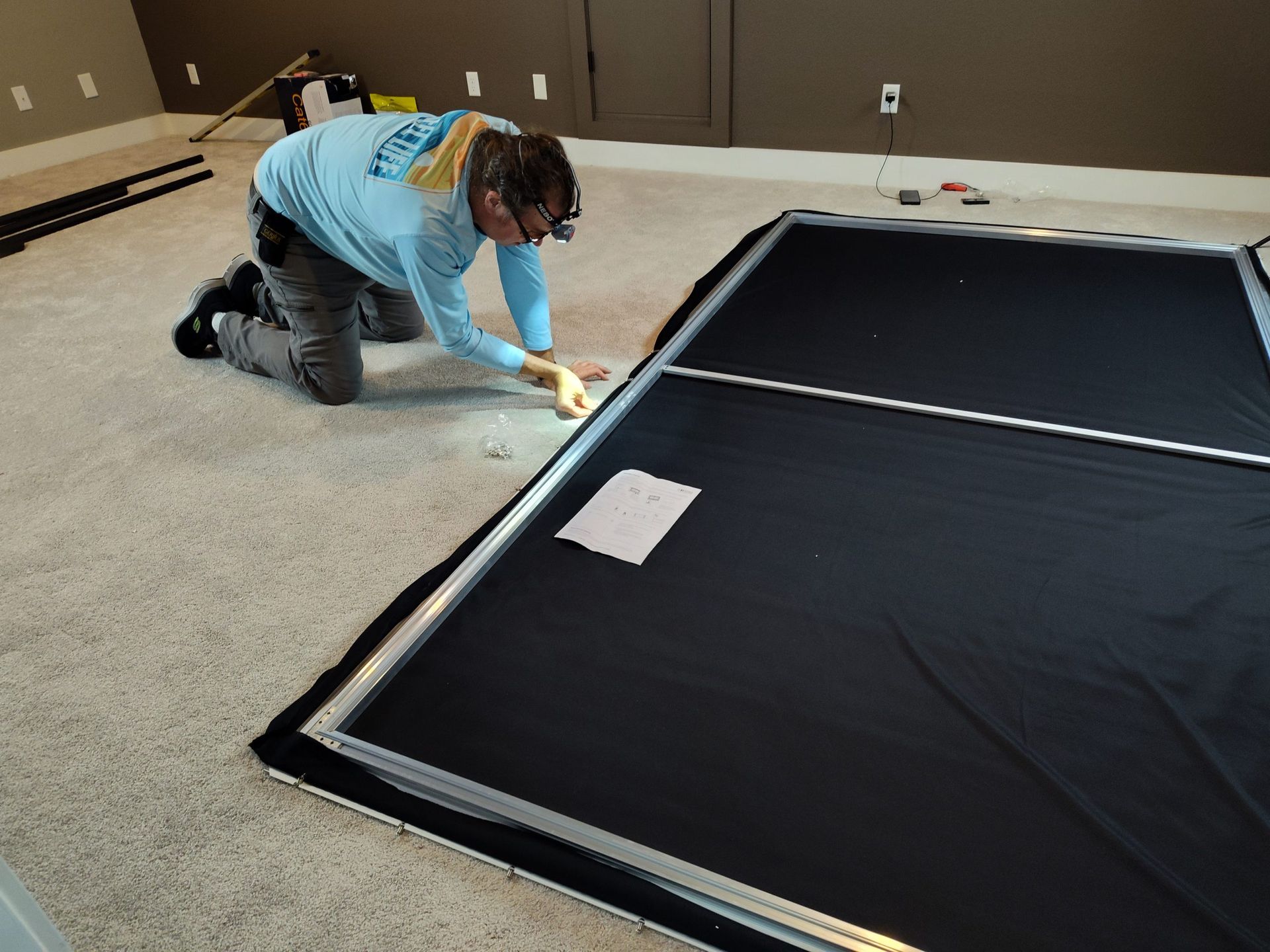 Man is Kneeling on the Floor Working on a Picture Frame — Austin, TX — ACA Electronics Inc.