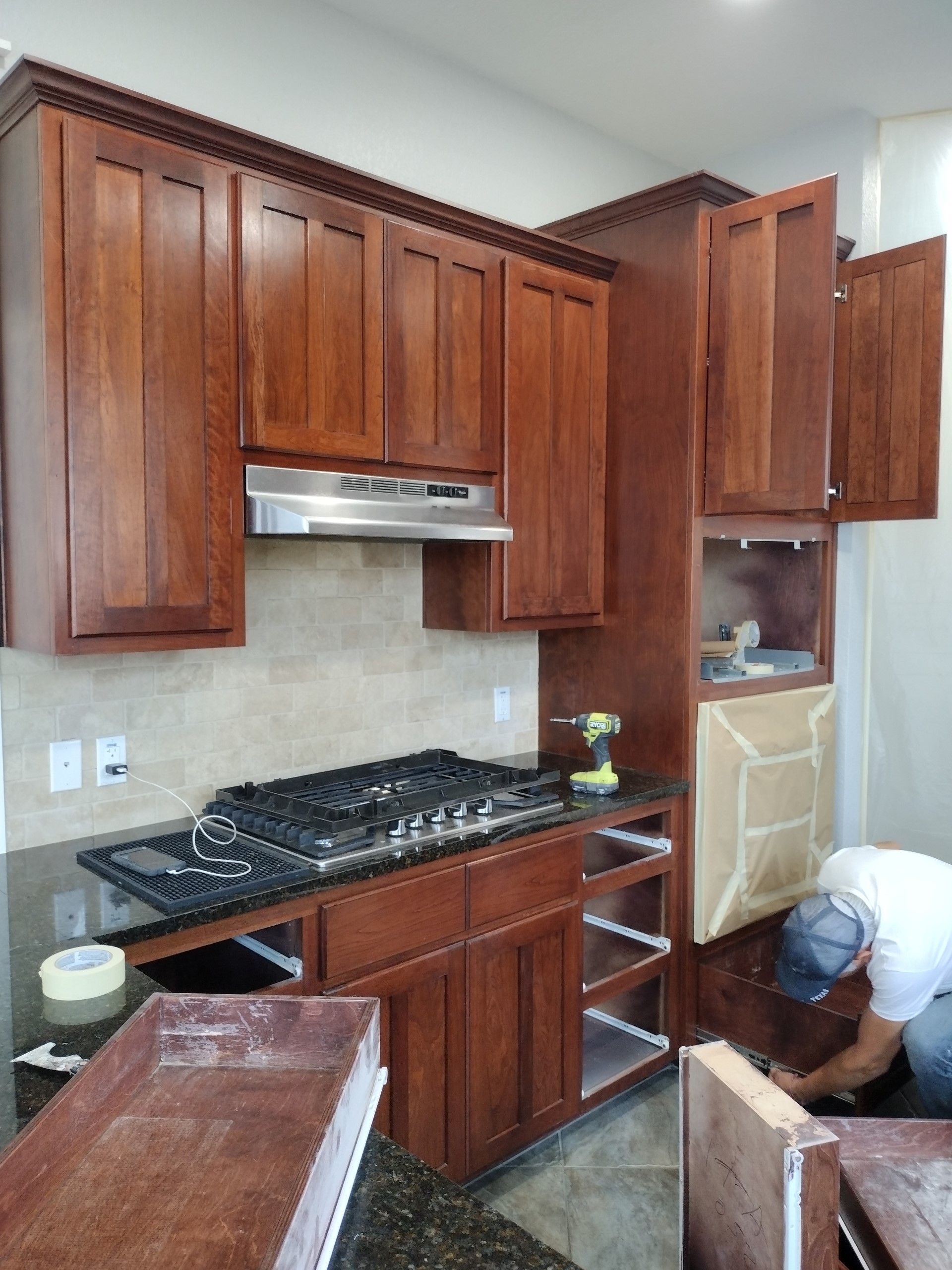 Man is Working in a Kitchen With Wooden Cabinets — Austin, TX — ACA Electronics Inc.
