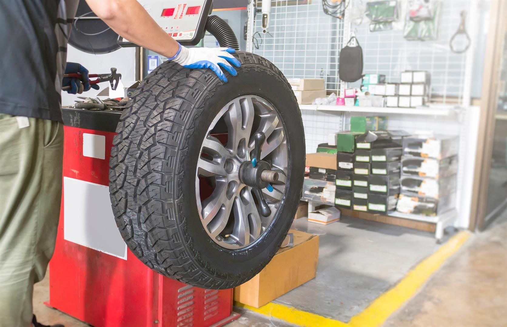 A  man is balancing a tire on a machine in a garage | Berkeley Bob's
