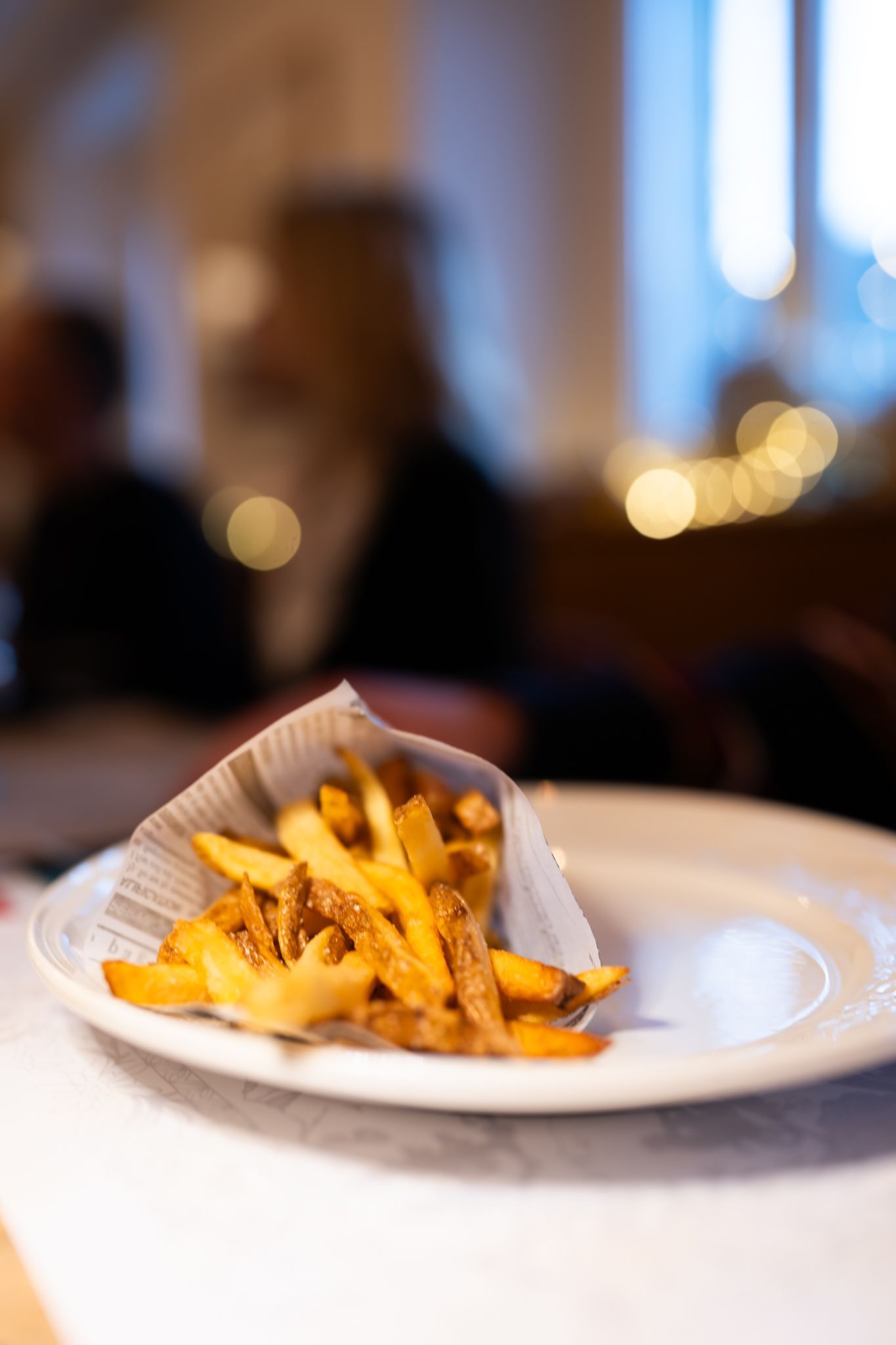 Cornet en papier de frites dorées posé sur assiette blanche, frites maison, POSTE|ROPRAZ Ropraz