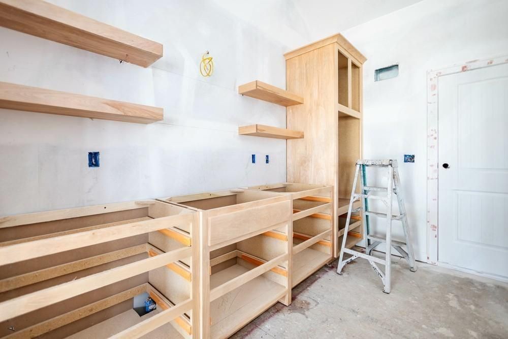 a ladder sits in a room with wooden cabinets under construction