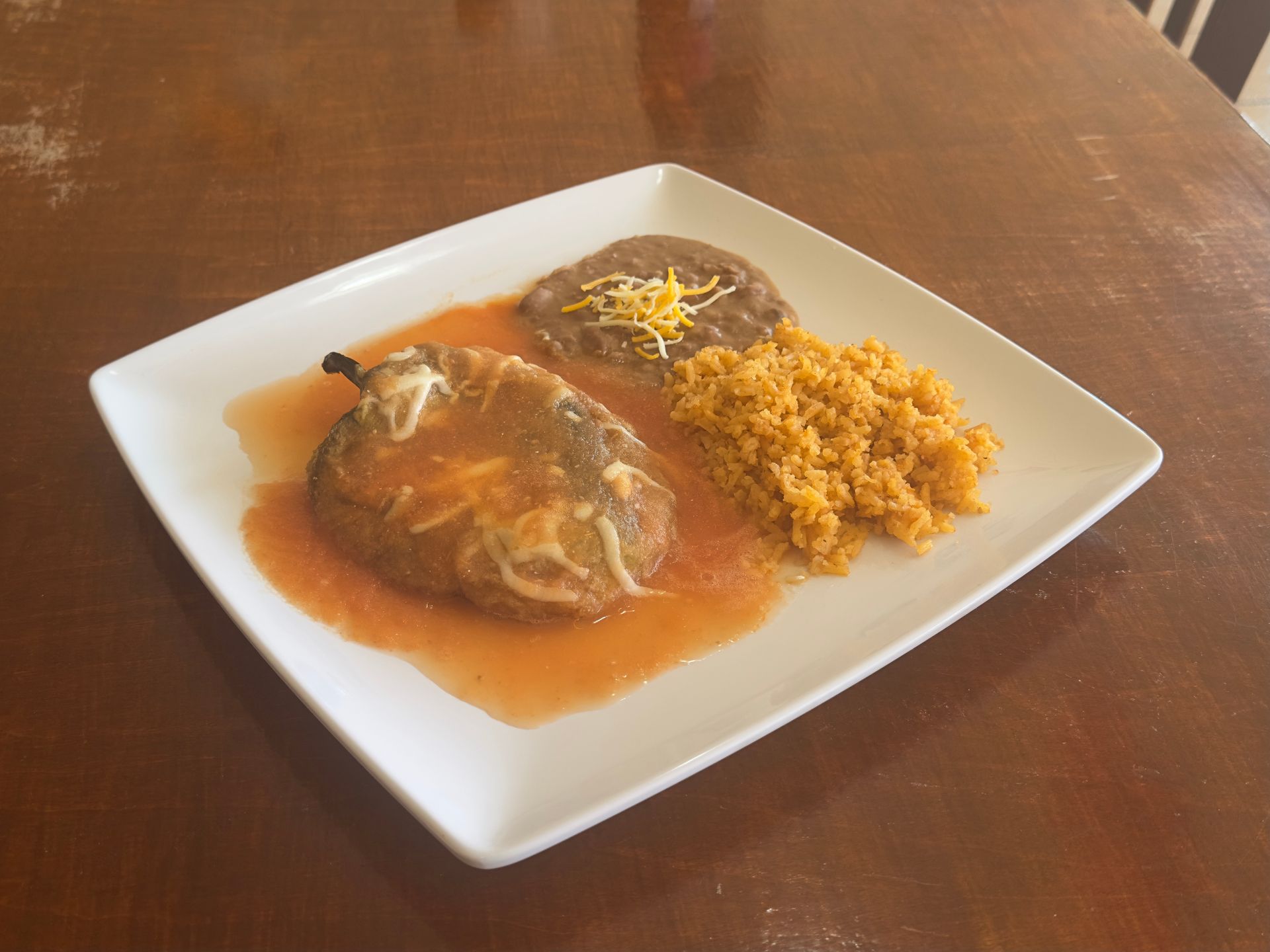 Plate of Mexican food: grilled meat, rice, beans, salad, and pickled jalapeño.