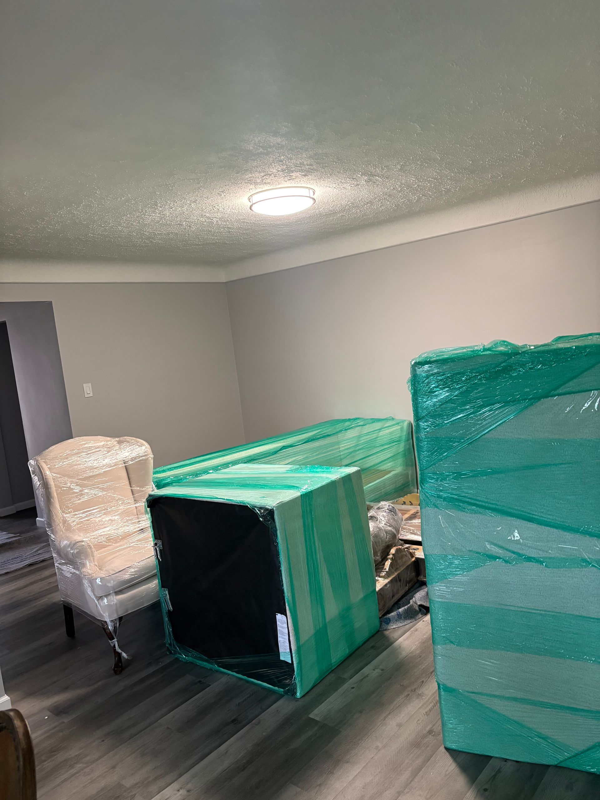 Office workers and a professional mover in a safety vest coordinate furniture relocation in a modern office space.