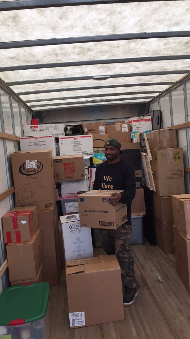 Two movers in matching blue uniforms load a white sofa into the back of a cargo van. Two movers in matching blue uniforms load a white sofa into the back of a cargo van.