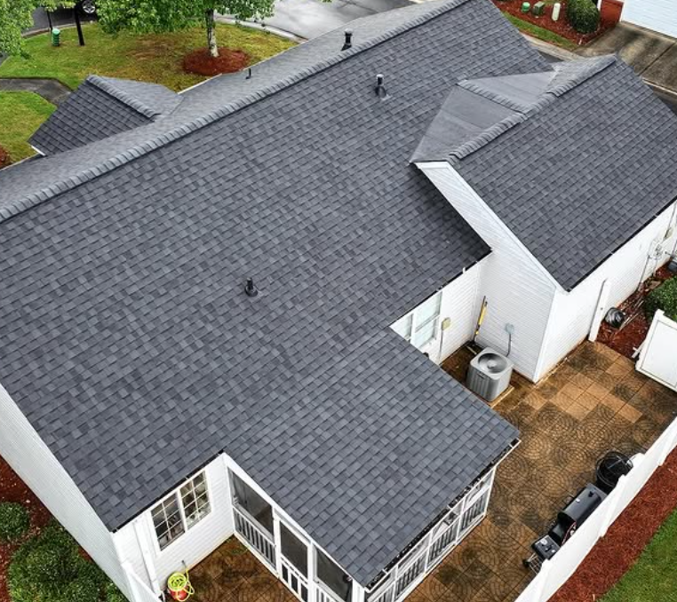 Overhead view of a house with a dark gray shingled roof, white siding, and a screened porch.