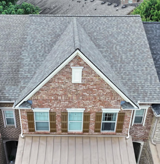Brick home with gray shingle roof, brown shutters, and white trim. Bird's-eye view.
