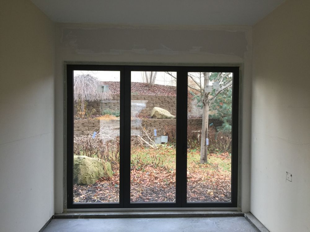 A room with three windows and a view of a garden.
