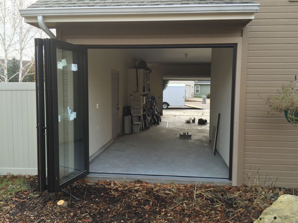 A garage with the door open and a white fence in the background