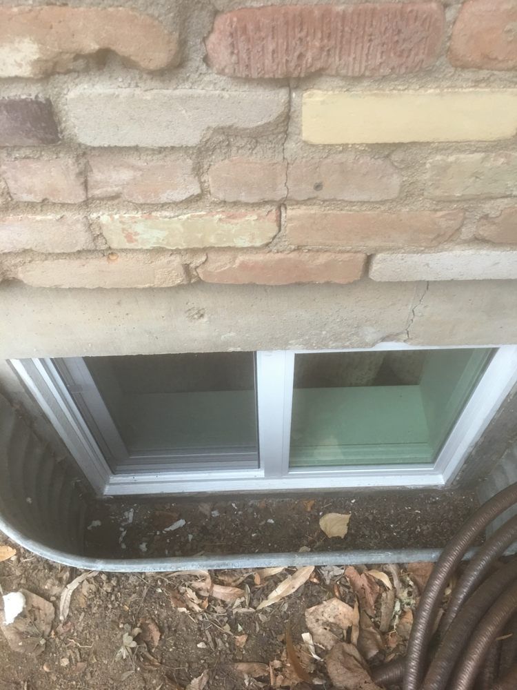 A window in a basement next to a brick wall.