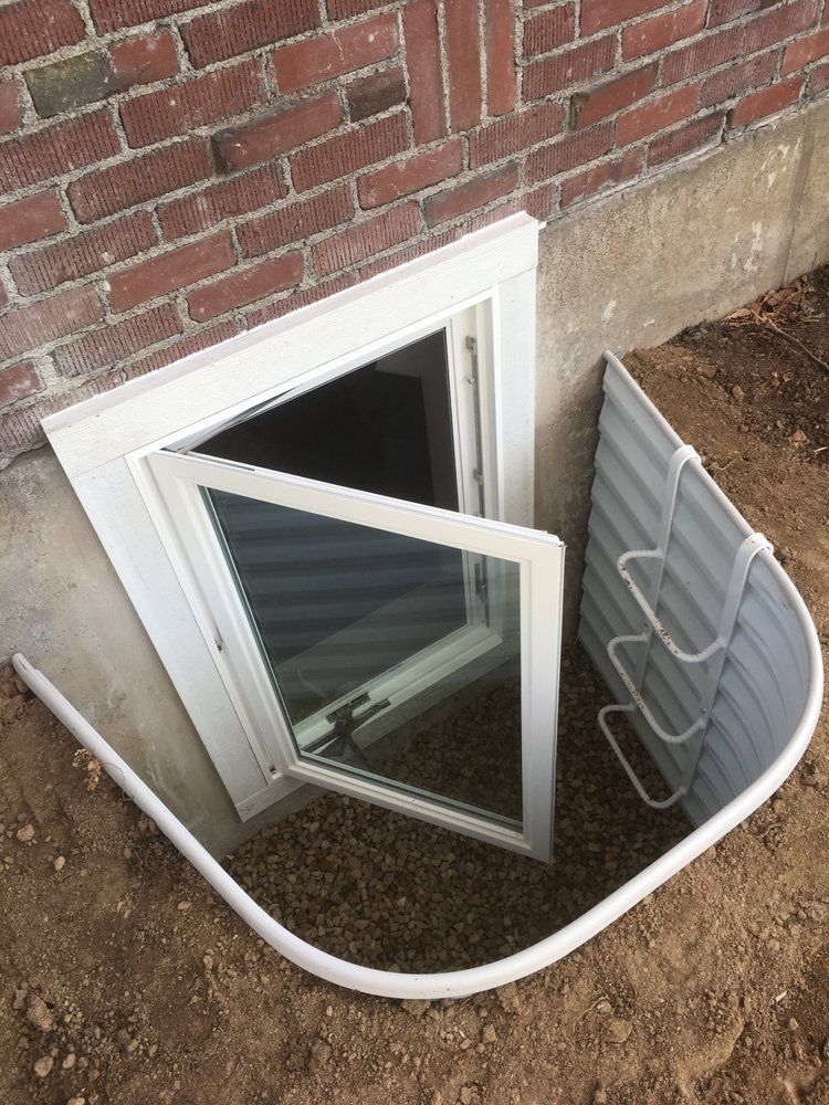 A window in the basement of a brick house with the door open.