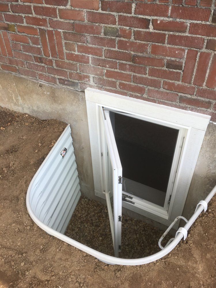 A window in the basement of a brick building with the door open.