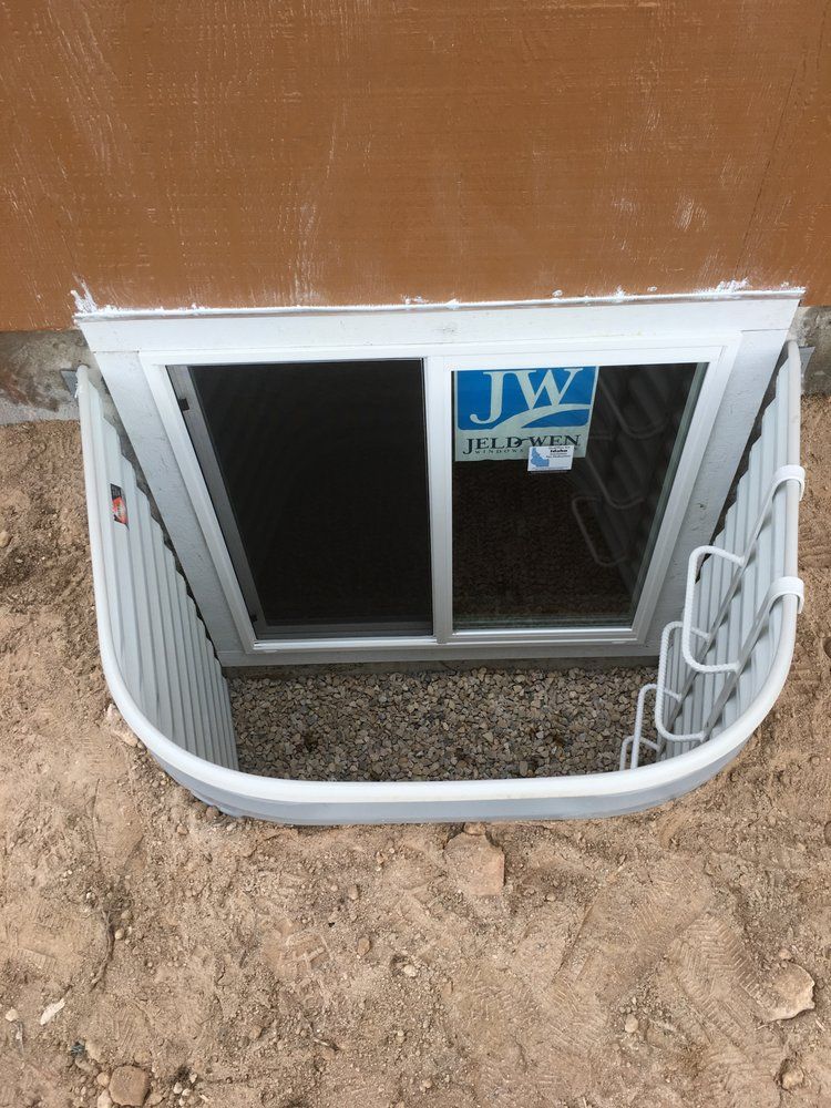 A window well in the ground next to a house.