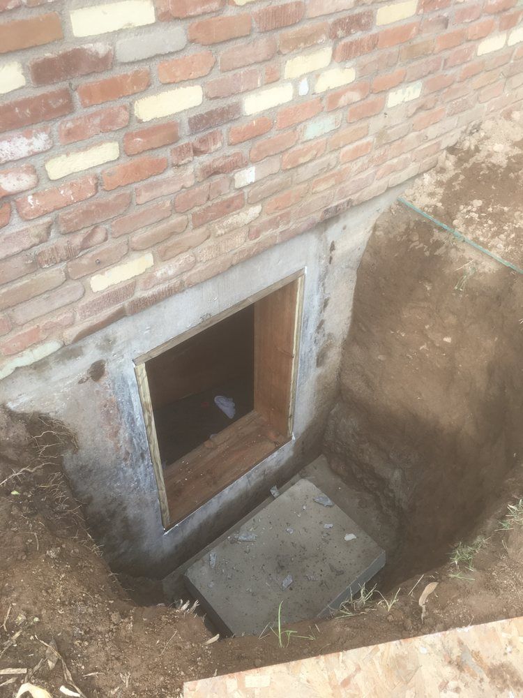 A brick wall with a window in it and a hole in the ground.