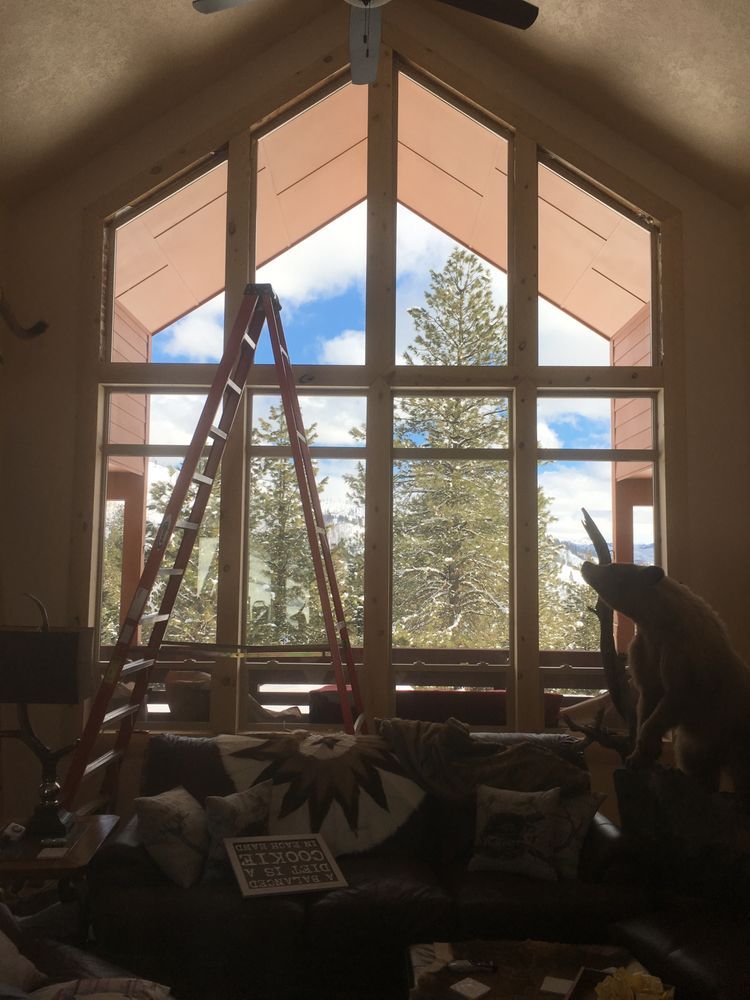 A living room with a ladder in front of a large window