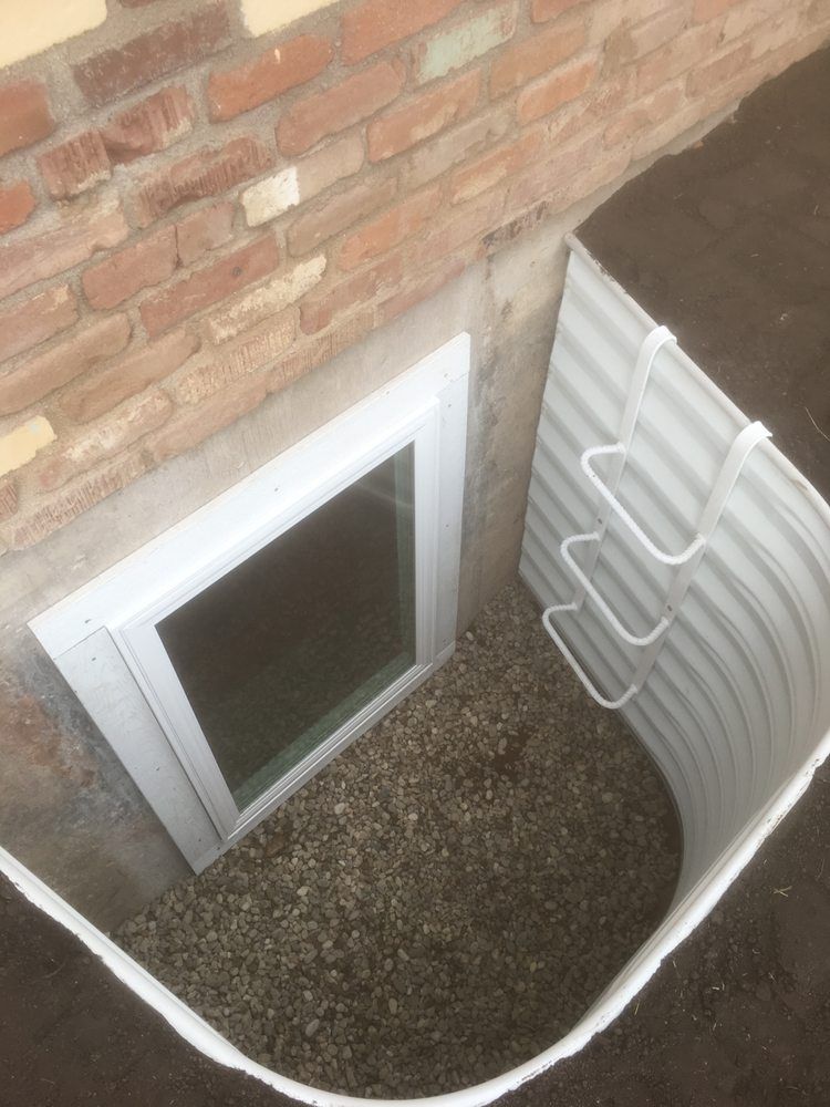 A window in a basement with stairs leading up to it.