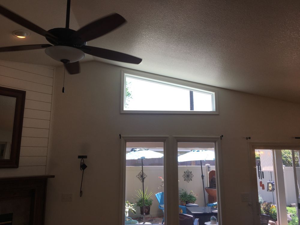 A living room with a ceiling fan and a large window