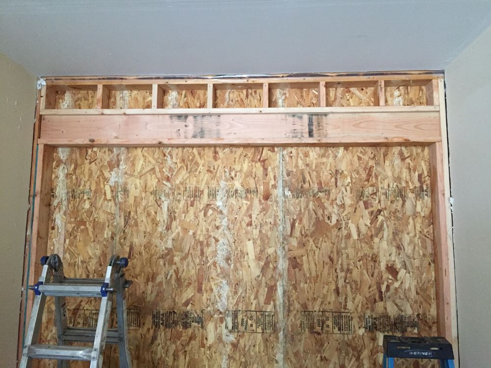 A ladder is sitting in front of a wooden wall.