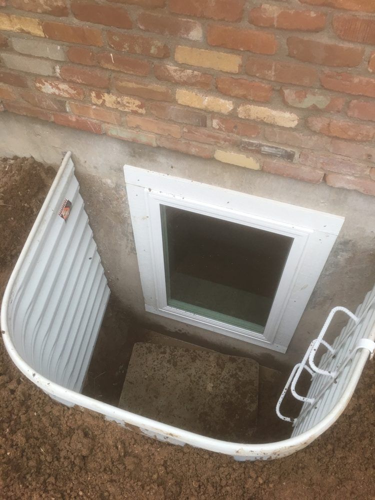 A window in a basement next to a brick wall.