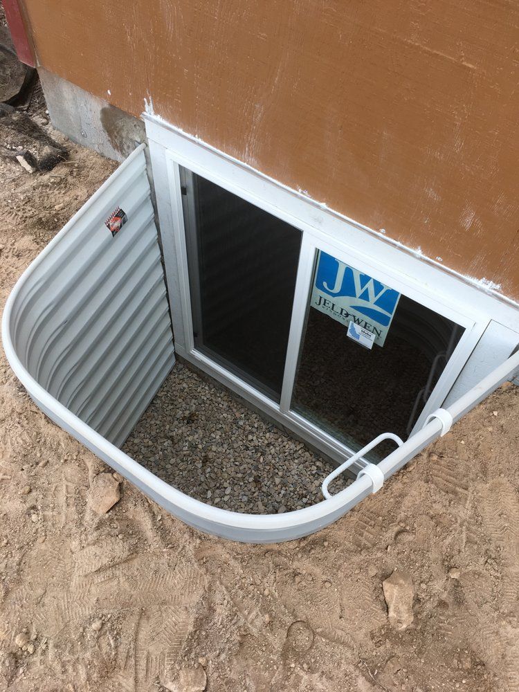 A window well in the ground next to a house.