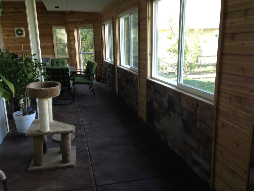 A screened in porch with a cat tree and chairs