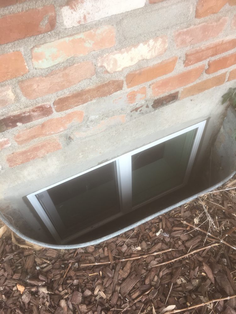 A window well in the side of a brick building.