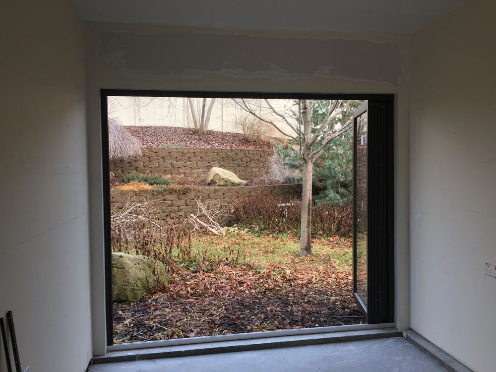 A room with a large window and a view of a garden.
