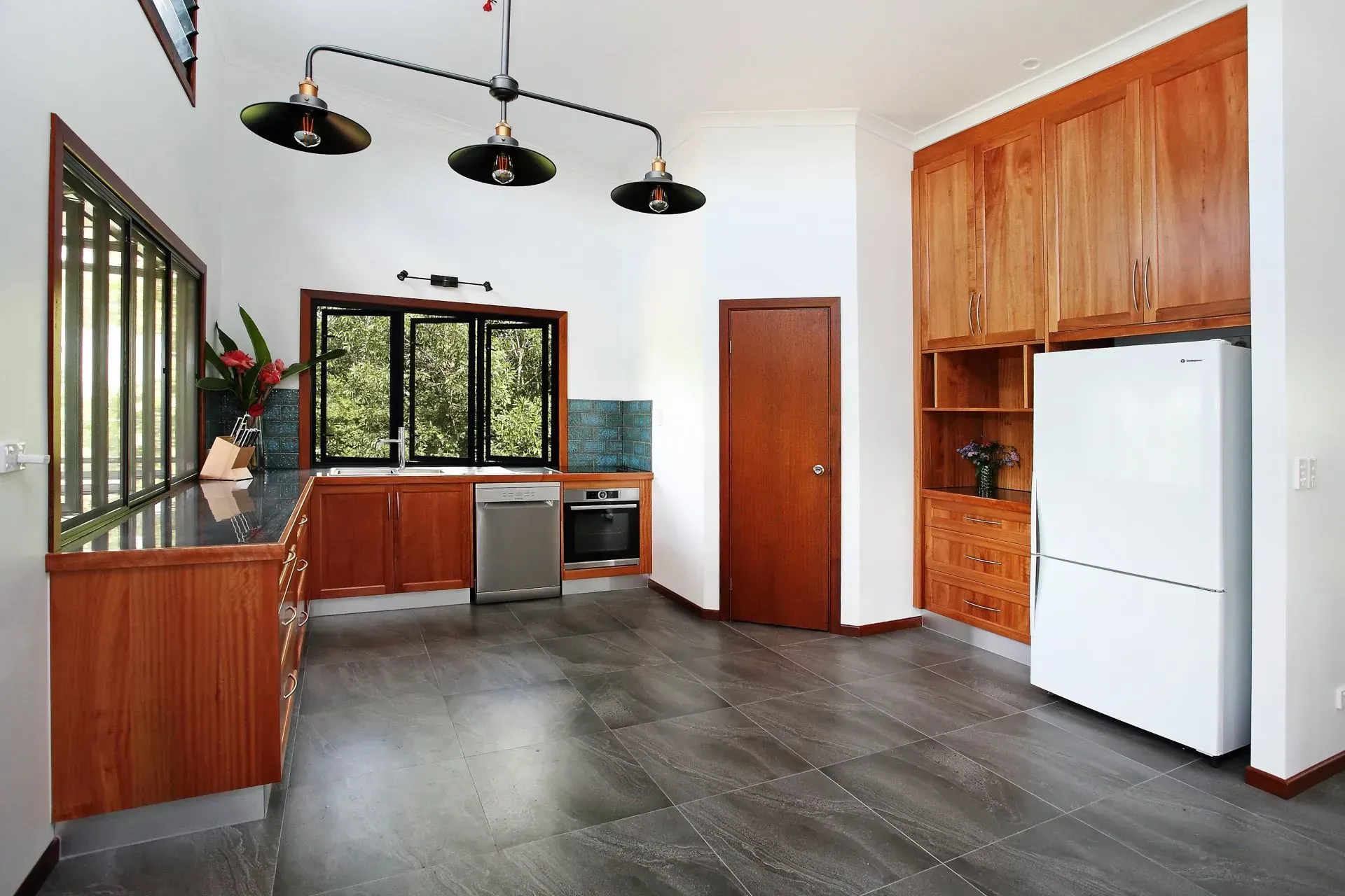 Kitchen With Wooden Cabinetry, Stainless Steel Appliances, And Dark Gray Flooring — B & C Cabinets in Mareeba, QLD