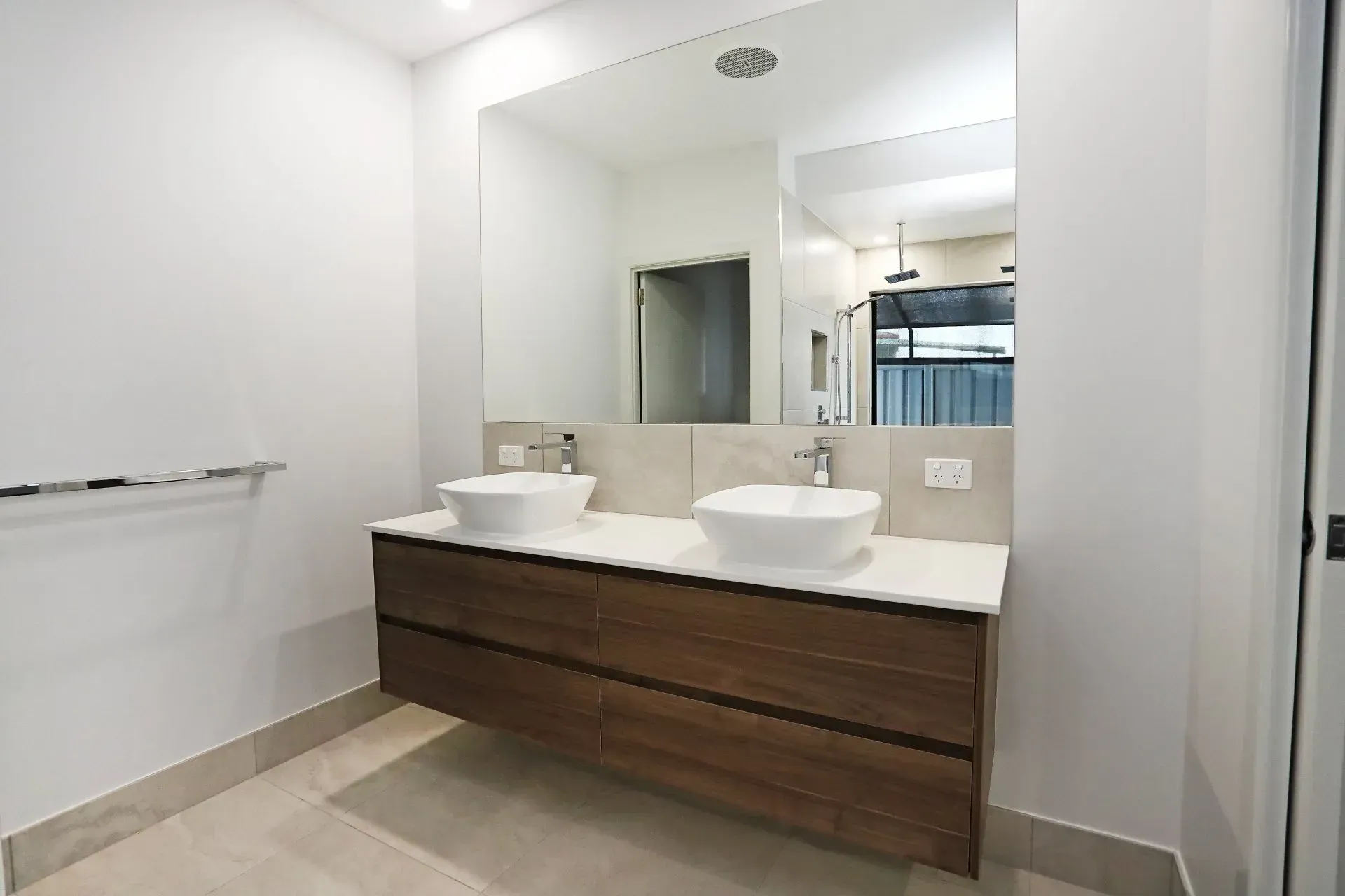 Modern Bathroom With Floating Wooden Vanity, White Sinks, Large Mirror, And Neutral-toned Walls And Floor — B & C Cabinets in Mareeba, QLD
