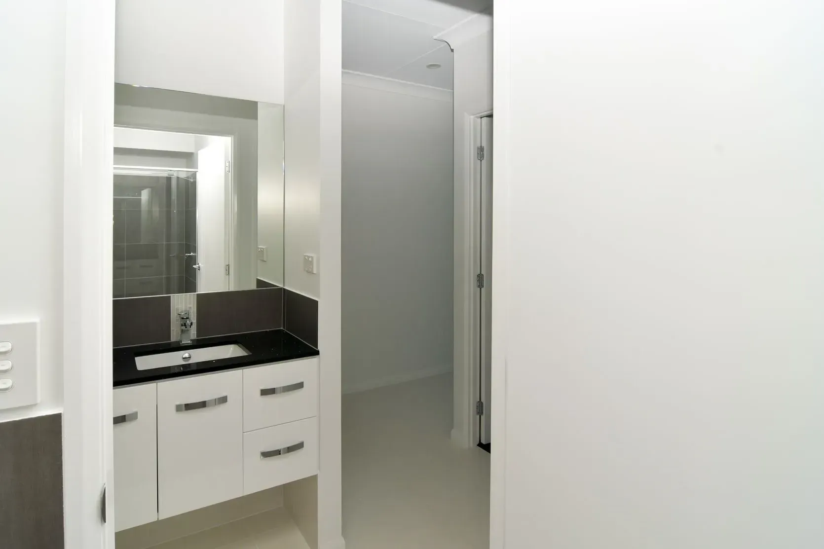 Bathroom Interior With White Cabinets, Dark Countertop, And Mirror Reflecting A Shower — B & C Cabinets in Mareeba, QLD