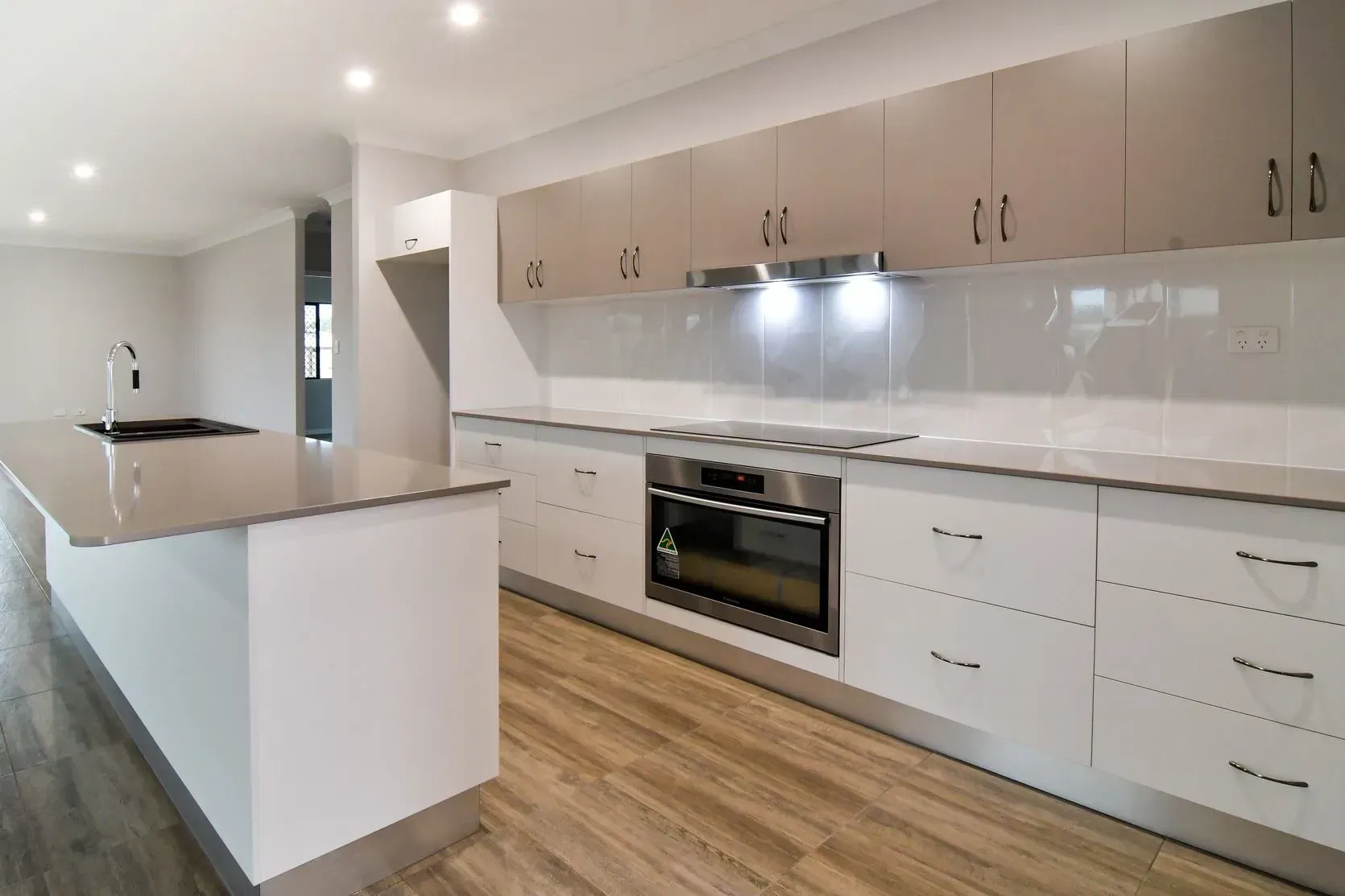 Modern Kitchen With White And Beige Cabinets, Stainless Steel Appliances, And A Large Island — B & C Cabinets in Mareeba, QLD