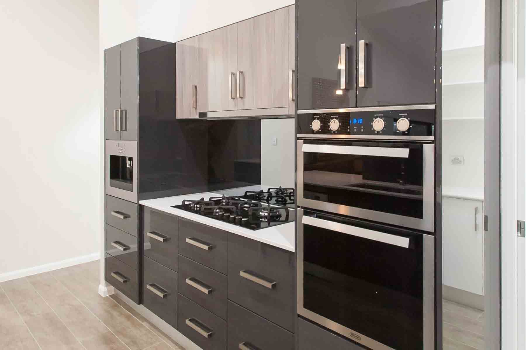 Modern Kitchen With Gray And Light Wood Cabinets, Built-in Oven, And Gas Stovetop — B & C Cabinets in Mareeba, QLD
