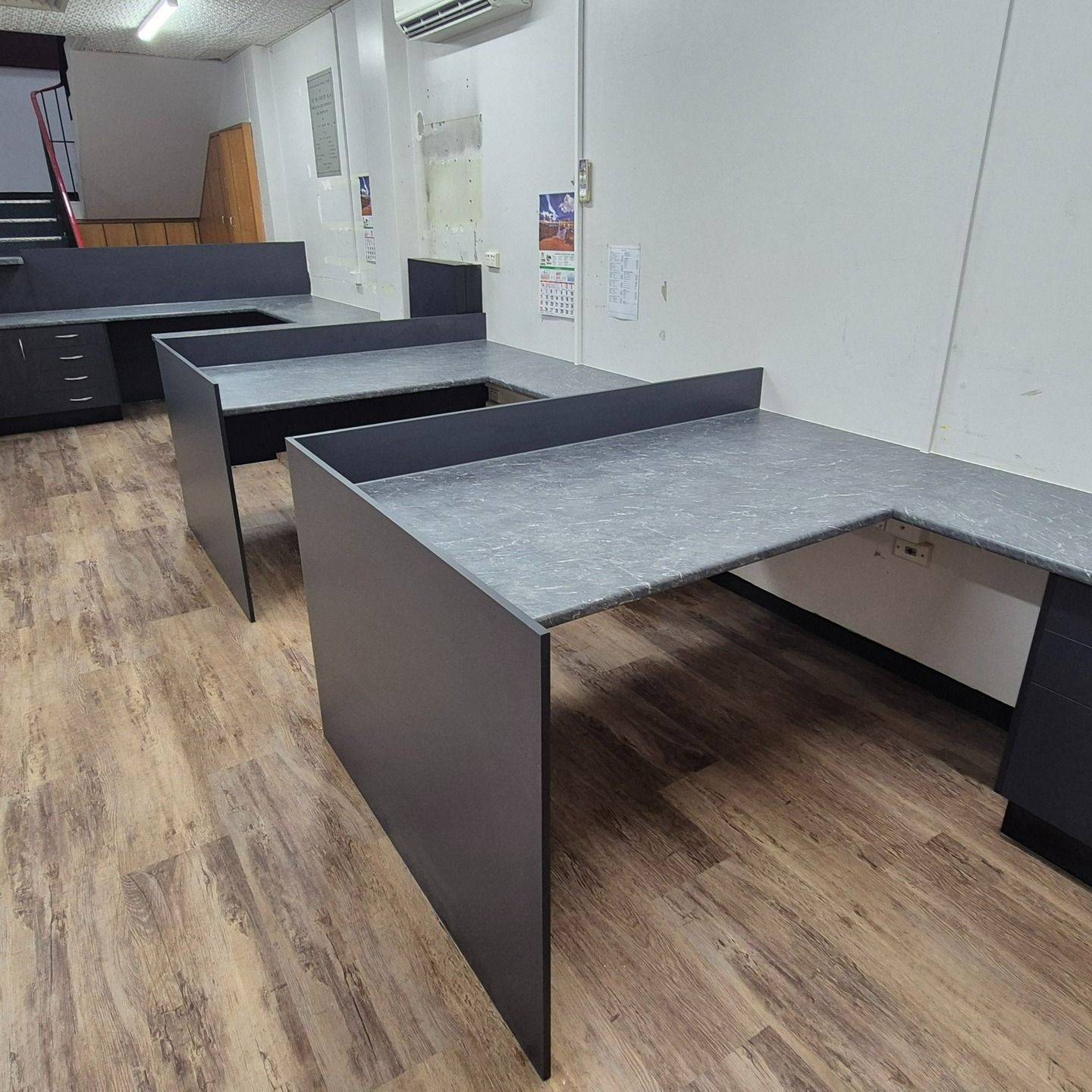 Office with gray desks arranged in an L-shape and facing forward, dark cabinets, wooden floor — B & C Cabinets in Mareeba, QLD