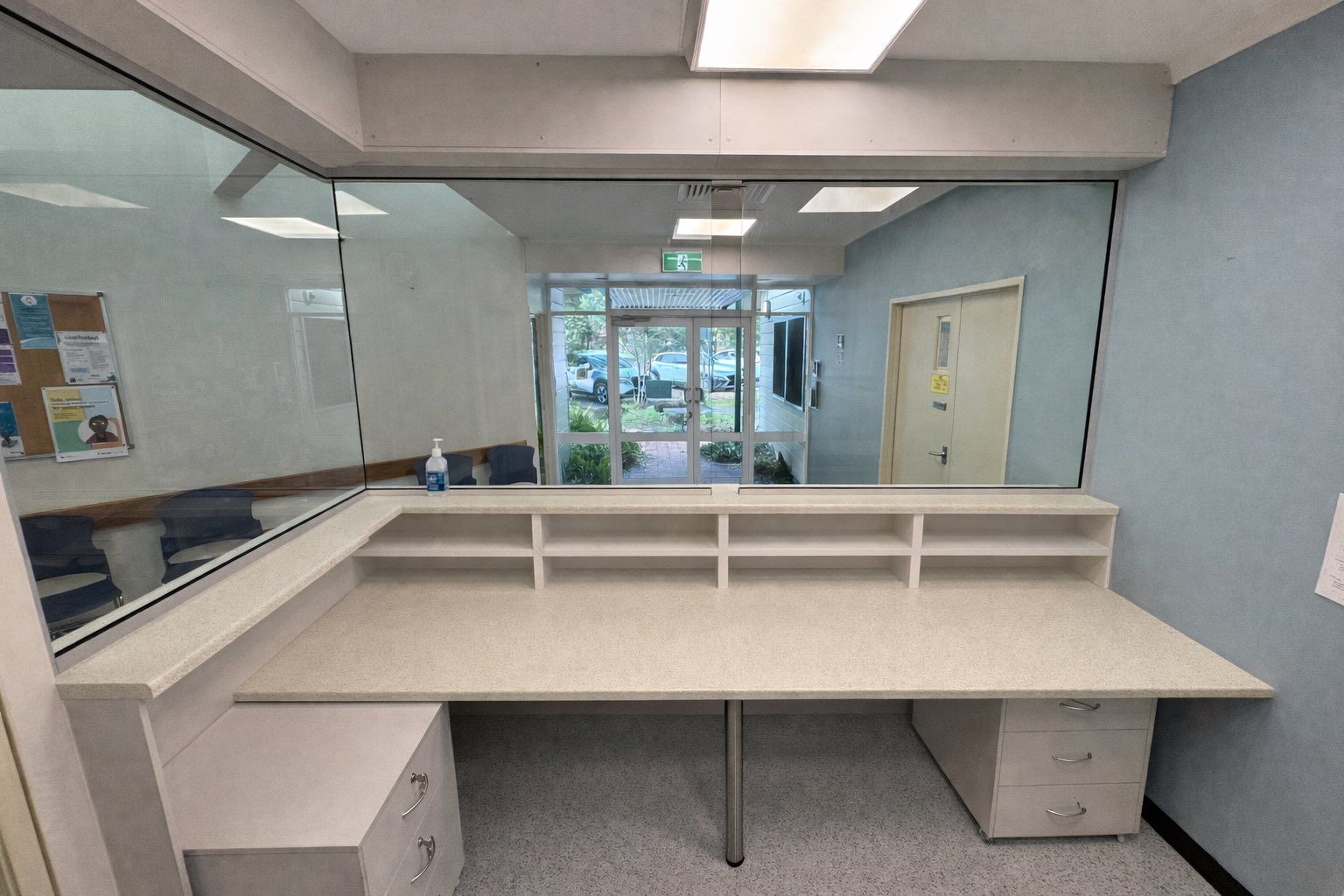 Reception Desk Behind A Large Window. Awaiting Area And Entrance Visible Through The Glass — B & C Cabinets in Mareeba, QLD