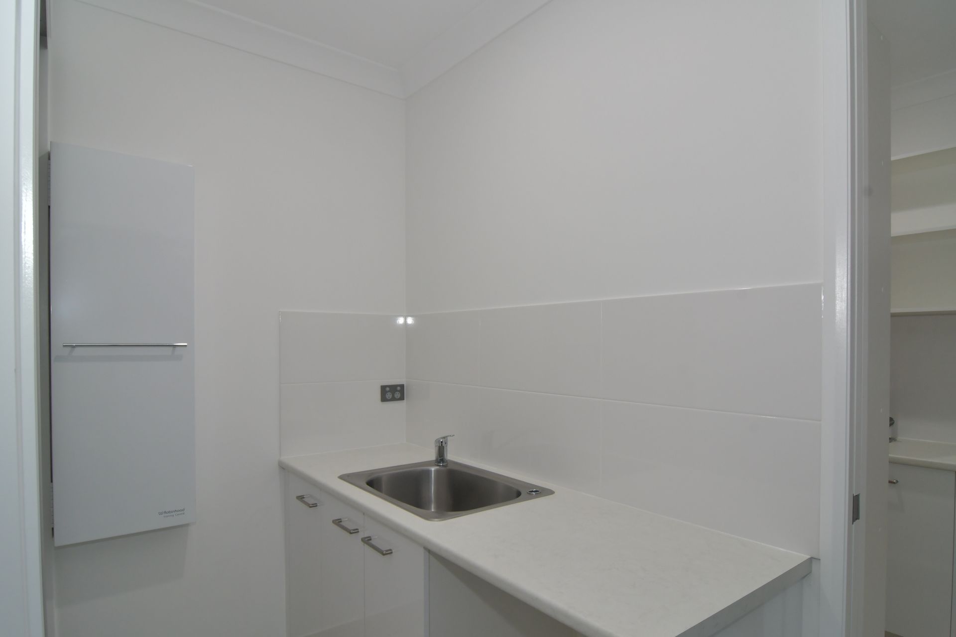 Laundry Room With White Cabinets, Sink, And Backsplash. A Towel Rack Is On The Left — B & C Cabinets in Mareeba, QLD